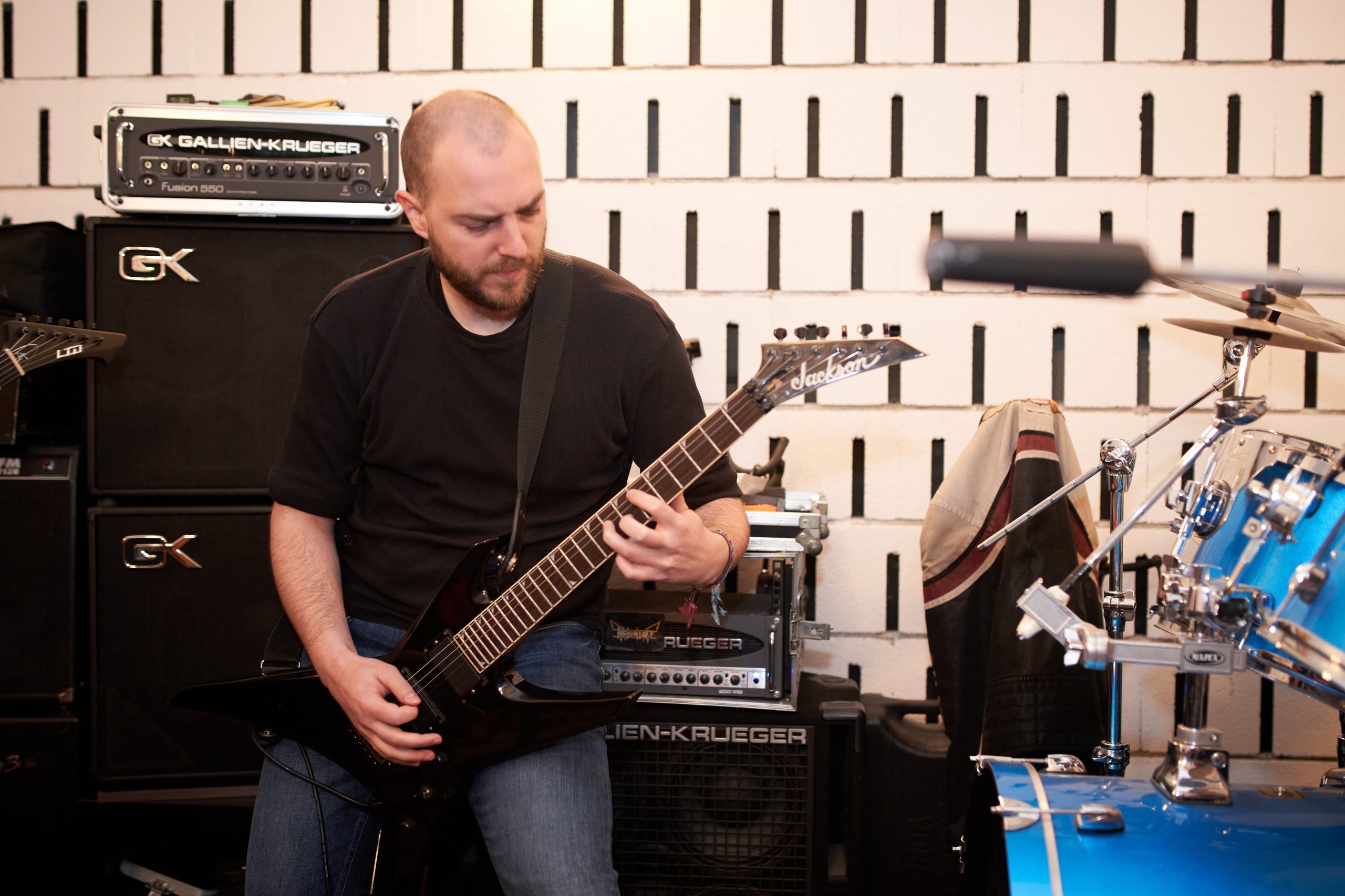 Guitarist playing next to amplifiers and a drum kit